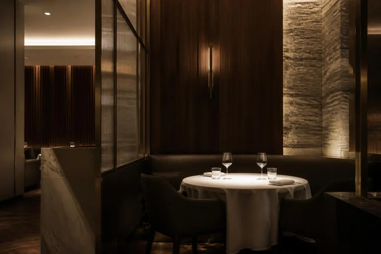 Vision Signature d'identité visuelle : salle de restaurant contemporain haut de gamme, boiseries sombres, pierre et laiton en lumière tamisée
